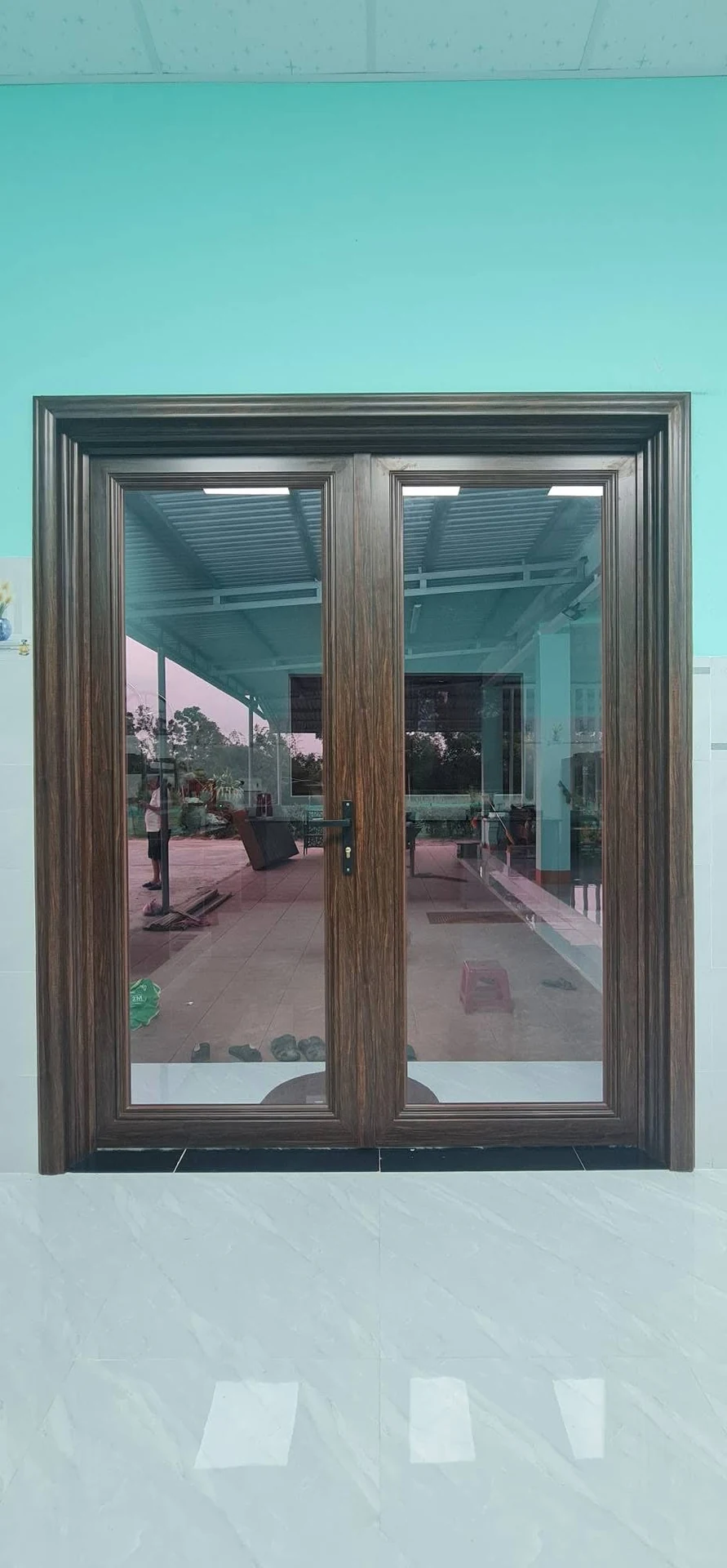 Cửa đi 2 cánh nhôm kính vân gỗ bản lớn có phào chỉ bao khung tường